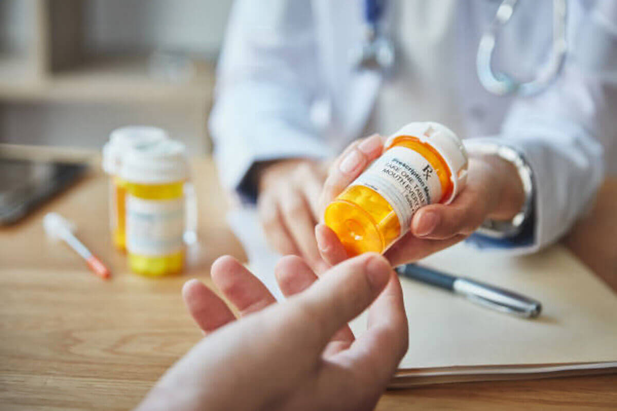 An image of a doctor handing a prescription to a patient in a clinic setting.