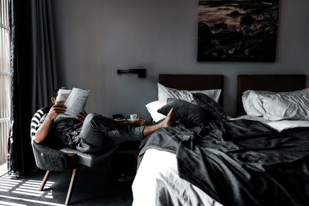 a man sits in a hotel room, reading a magazine