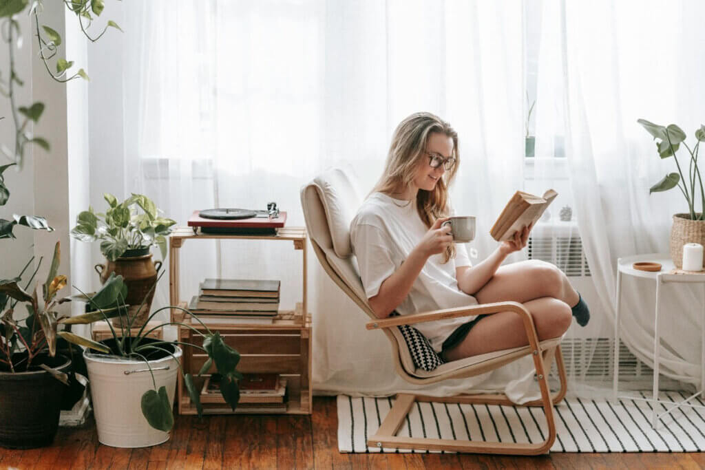 woman sitting in a a well lit room, reading with a cup of tea