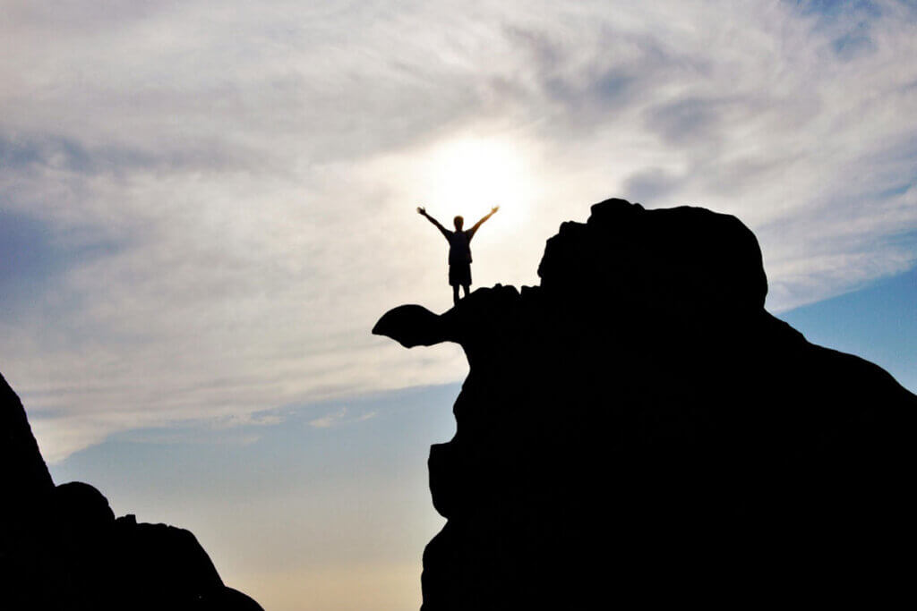 A person standing on top of a mountain with arms stretched out.