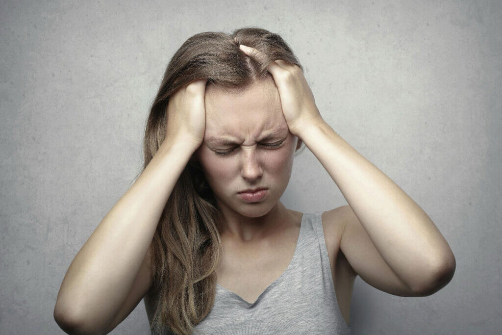 A woman holding her head while looking distressed.