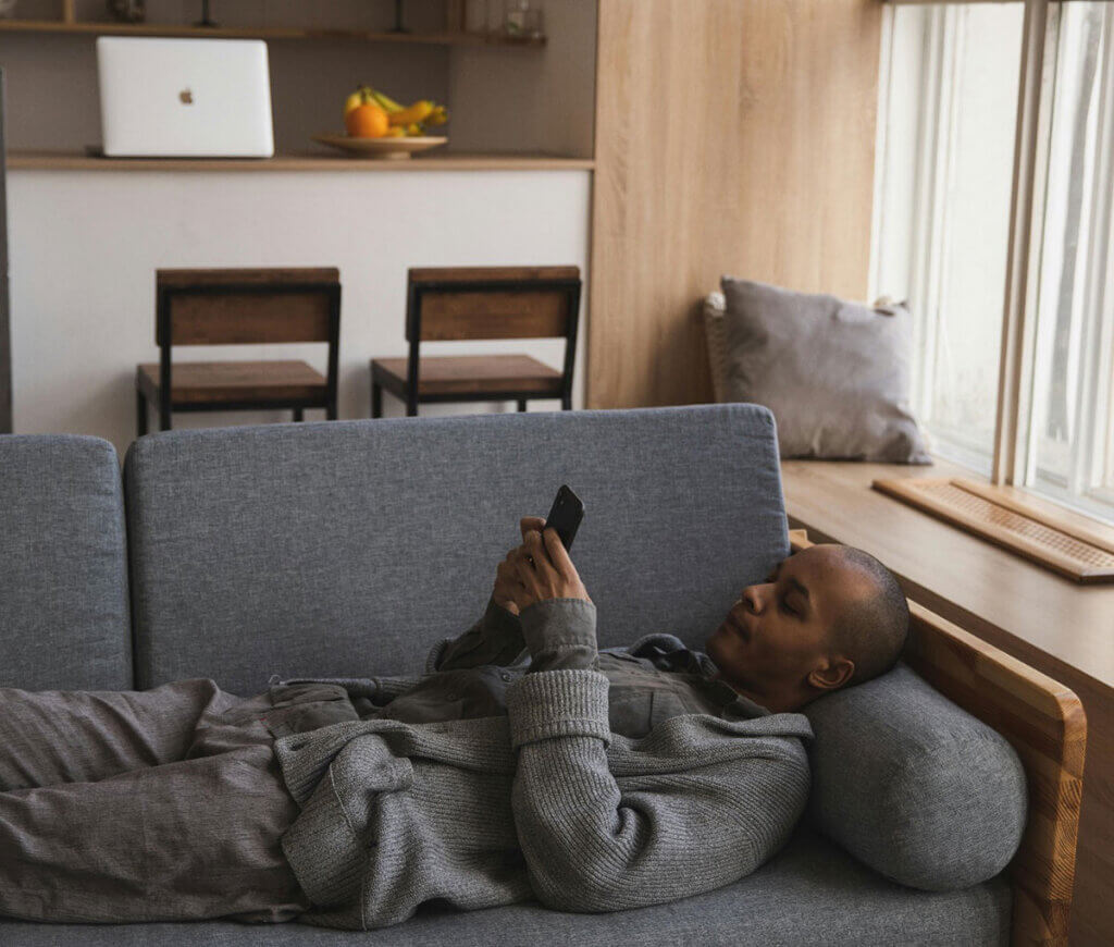 A man lying on a couch using a phone.