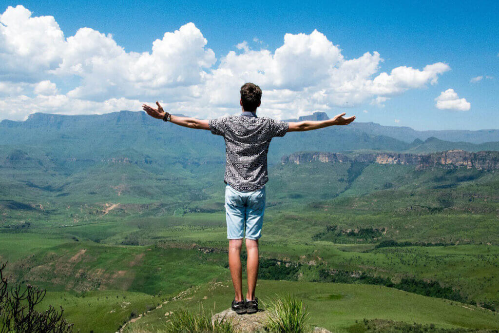 A man standing on a rock with his arms outstretched.