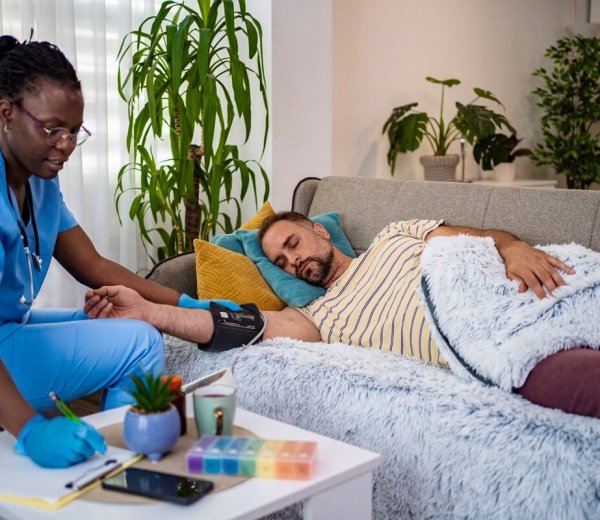 Nurse checks vital signs of relaxed patient in cozy setting.