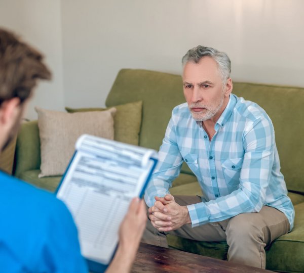 Male patient looking at a physician with a clipboard